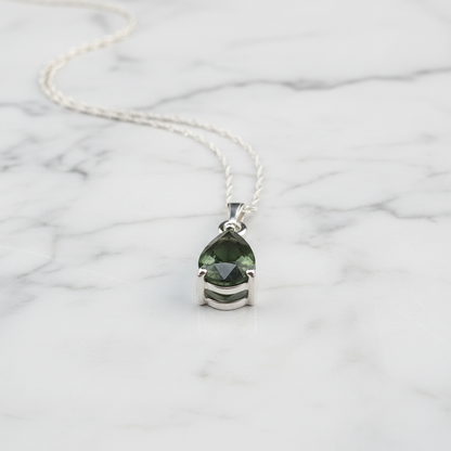 Moldavite pendant detail on white marble